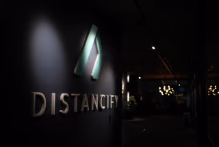 Distancifys upplysta symbol och logotyp på en mörk vägg vid kontorets korridor.